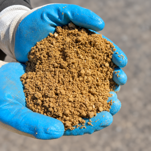 Crusher Dust vs Roadbase Decomposed Granite Gold held in blue and white gloves