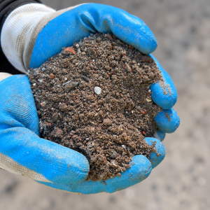 Crusher Dust vs Roadbase Crusher Dust/ Recycled Filling Sand held in blue and white gloves