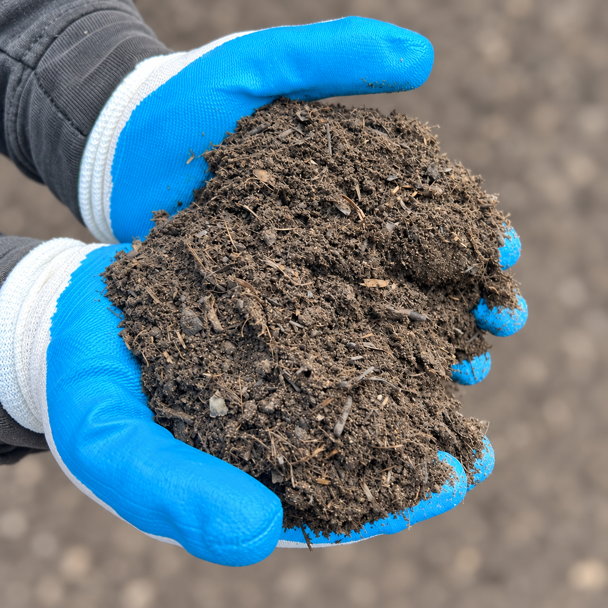 Super Grow Premium Garden Mix – square gloved sample Super Grow Premium Garden Mix held in blue and white gloves against softly blurred ground